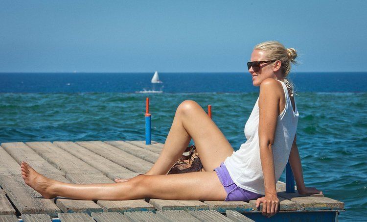 Synnøve Macody Lund at the beach wearing a white sando and violet short