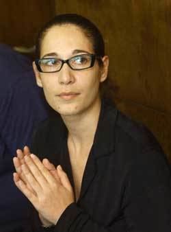 Tali Fahima looking afar with folded hands and wearing eyeglasses and black long sleeve blouse