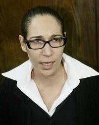 Tali Fahima with tied up hair while wearing a black and white blouse and eyeglasses
