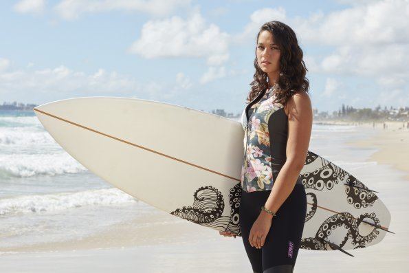 Tamala Shelton standing at the beach in her swimwear while carrying a skateboard