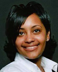 Tamika Huston smiling and sporting short hair and wearing a white collared shirt.