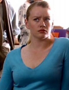 Tamzin Malleson looking at something with an angry face while wearing a blue blouse