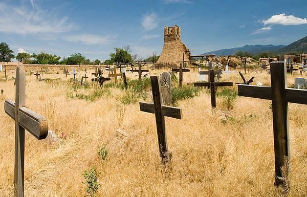 The old cemetery at Taos Pueblo, New Mexico with crosses and a ruined old original church in the background.