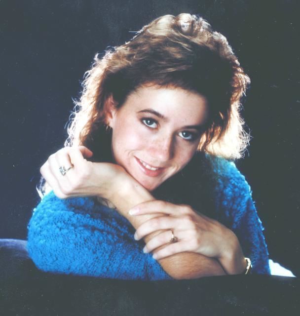 Tara Calico smiling while wearing a blue blouse, bracelet, and rings