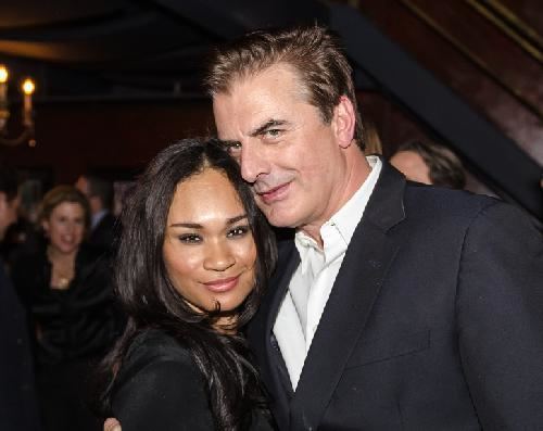 Tara Lynn Wilson smiling and wearing black dress while Chris Noth wearing black coat and white long sleeves