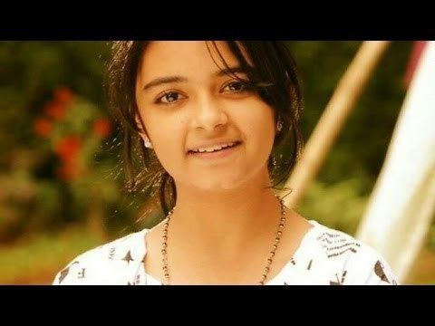 Taruni Sachdev smiling while wearing a black and white t-shirt, necklace, and earrings