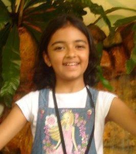 Taruni Sachdev smiling while wearing a denim jumpsuit and white t-shirt