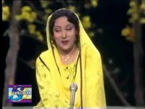Tassawar Khanum singing on stage and wearing a yellow dress and veil with her eyes closed.