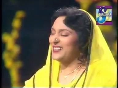 Tassawar Khanum singing on stage and wearing a yellow dress and veil with her eyes closed.