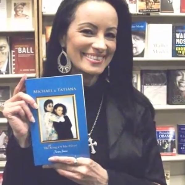 Tatiana Thumbtzen smiles while holding the book "Michael & Tatiana"