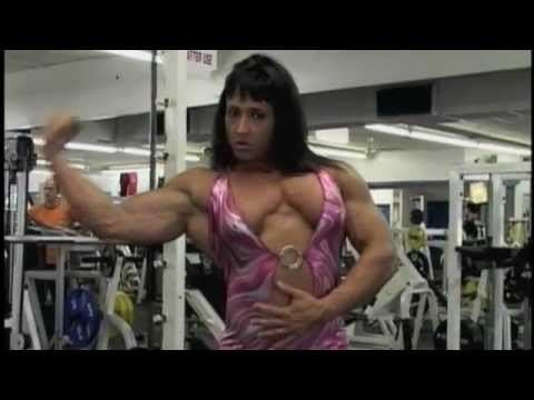 Tazzie Colomb flexing her muscles while wearing a pink bodysuit