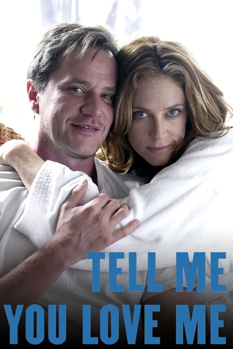 Poster of Tell Me You Love Me, a 2007 American cable television drama series starring Tim DeKay smiling and Ally Walker is with a serious face while hugging Tim. Tim is wearing a white shirt while Ally is wearing a white robe.