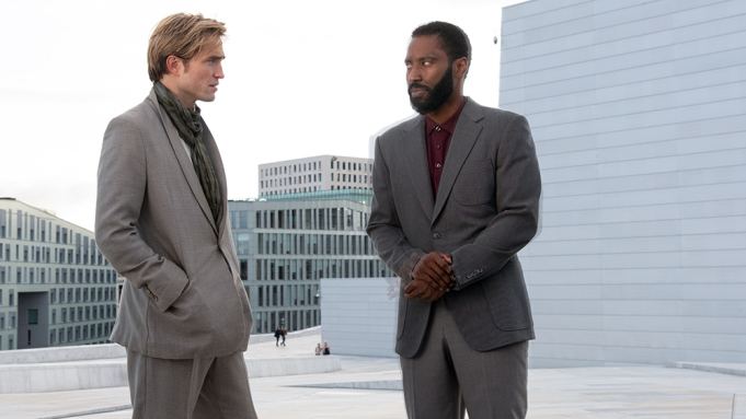 Robert Pattinson talking to John David Washington in the rooftop and both wearing a gray suit in a scene from the 2020 film "Tenet"