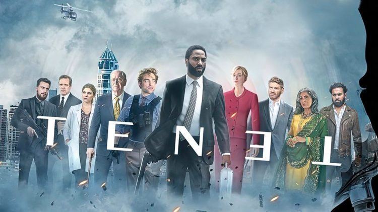 John David Washington holding a gun, carrying a case, and wearing a white sleeve under a gray suit with all the cast of the 2020 film "Tenet"