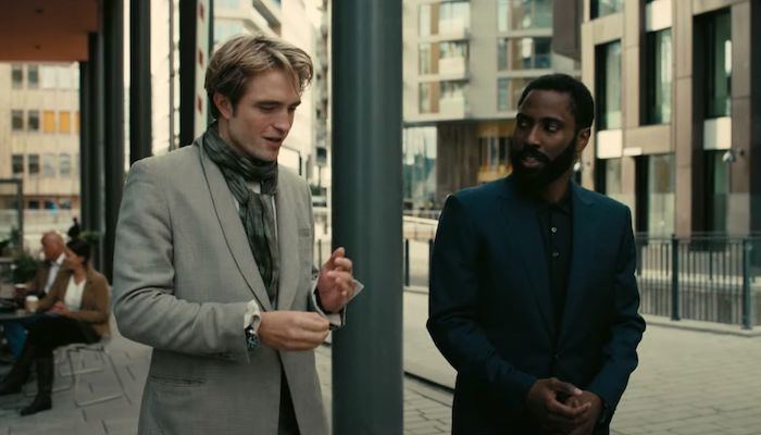 Robert Pattinson talking to John David Washington while walking and both wearing a suit in a scene from the 2020 film "Tenet"