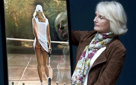 Fiona Walker looking at the original copy of the Tennis Girl poster and she is wearing a brown coat, white inner blouse, and scarf