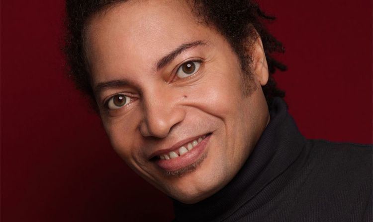 Terence Trent D'Arby smiling while wearing a black turtleneck shirt