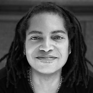 Terence Trent D'Arby with a tight-lipped smile and twist hairstyle while wearing a necklace and t-shirt