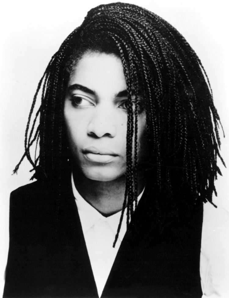 Terence Trent D'Arby looking on his side with a box braid while wearing a vest and long sleeves
