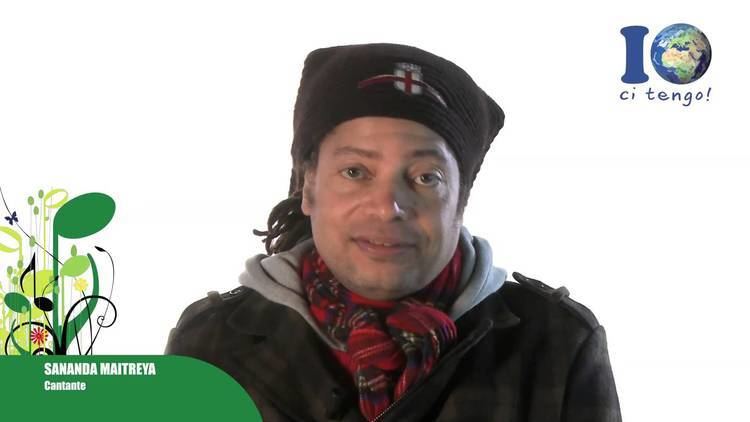 Terence Trent D'Arby with a tight-lipped smile while wearing a black and red checkered scarf, black bandana, and black and gray jacket