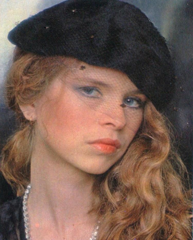 Teresa Ann Savoy looking fierce with her blonde hair down and wearing a black hat and pearl necklace