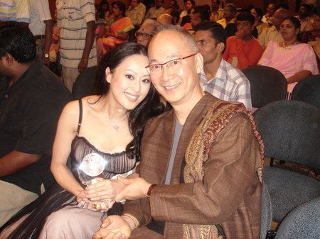 Teresa Cheung smiling and posing with Chen Yaomin and wearing a sleeveless black silk dress.