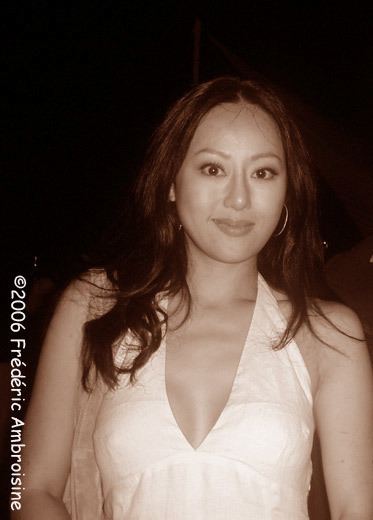 Teresa Cheung smiling closed mouth and carrying her shoulder bag and wearing a white sleeveless dress.