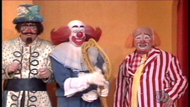 Bozo smiling while holding a mirror while Wizzo and Cooky the Cook are beside him in a scene from The Bozo Show