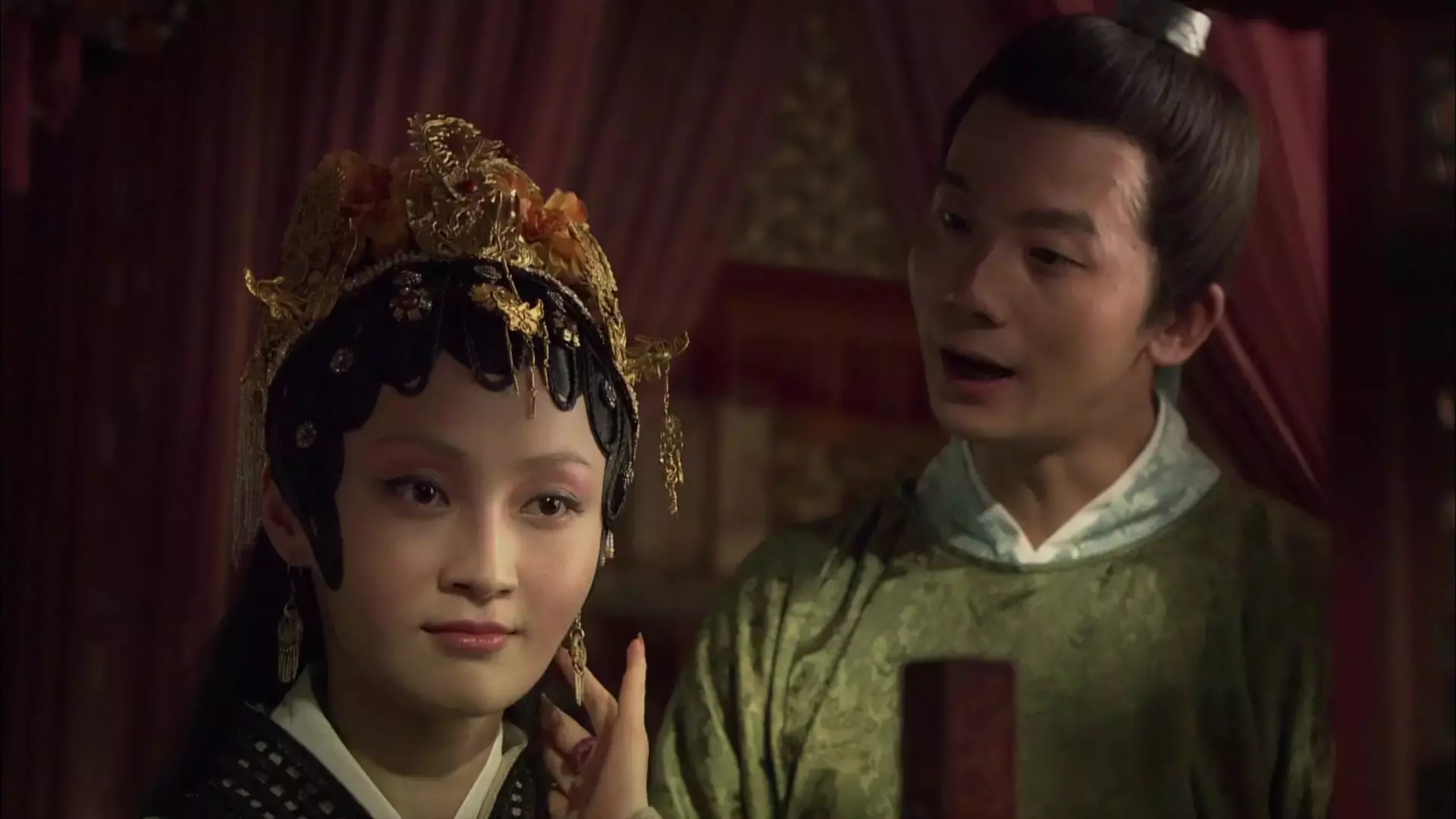 Mengjie Jiang with a serious face with a man talking to her. Mengjie wearing a headdress in a scene from The Dream of Red Mansions, a 2010 Chinese television series.