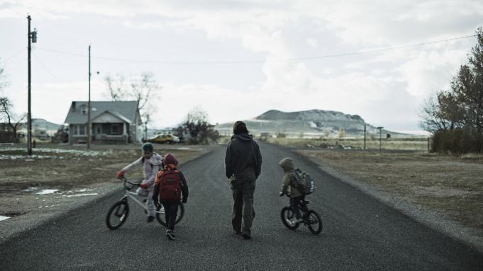 Clayne Crawford is walking while Arri Graham, Ezra Graham, and Jonah Graham are riding on a bicycle in a scene from the 2020 drama film, The Killing of Two Lovers