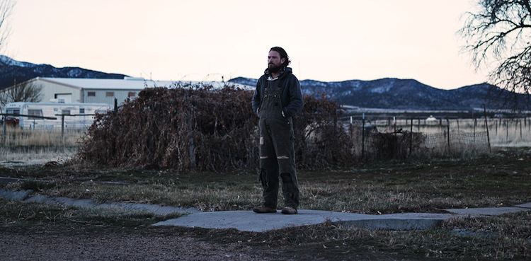 Clayne Crawford looking afar while wearing a hoodie and jumpsuit in a scene from the 2020 drama film, The Killing of Two Lovers