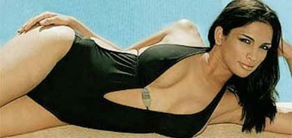 Miriam Rivera lying beside a swimming pool, with a fierce look, black hair, and wearing a sexy black swimsuit.