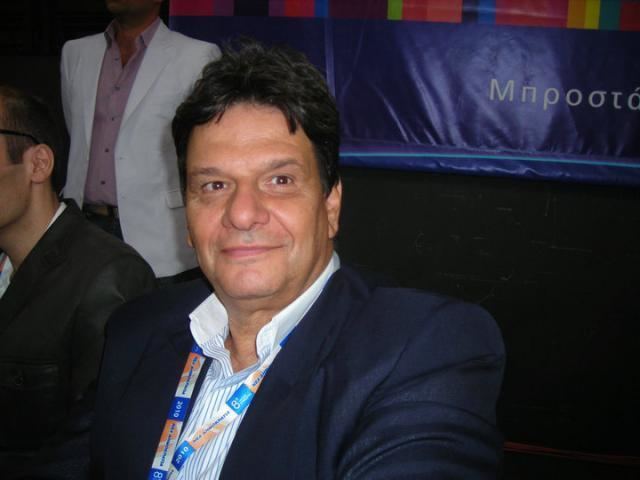 Thierry Roussel while sitting in an event wearing a white shirt and a black suit