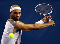 Thomas Blake playing tennis while wearing a white sweatband and white shirt