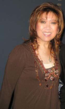 Tillie Moreno smiling while wearing a brown long sleeve blouse and necklace