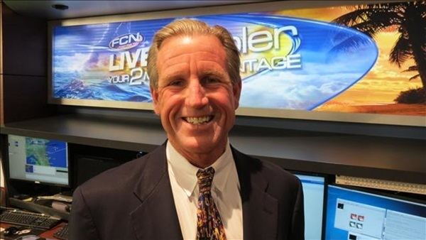 Tim Deegan smiling while wearing black coat, white long sleeves and neck tie