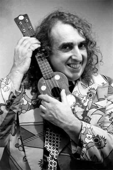 Tiny Tim with curly hair, wearing a suit and holding a ukelele.