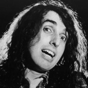 Tiny Tim with curly hair and wearing a checkered suit.