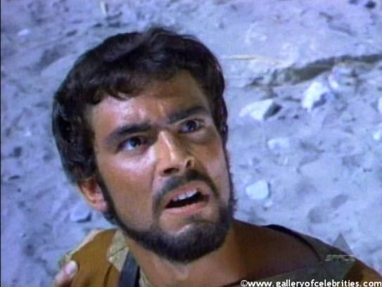 In the movie scene of Jason and the Argonauts 1963 Film, Todd Armstrong is shocked, standing looking to the left upward, has black hair beard and mustache wearing a brown shirt.