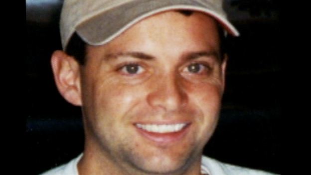 Todd Beamer smiling while wearing a brown cap and white t-shirt