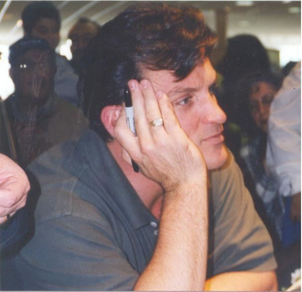 Young Tom Eplin wearing black polo shirt while hands on his face