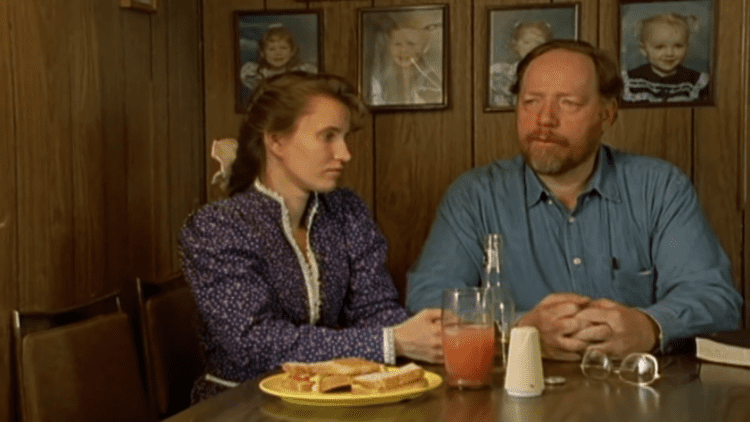 Tom Green sitting next to her wife while wearing blue long sleeves