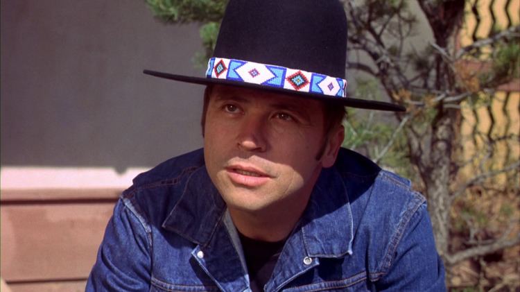 Tom Laughlin wearing a black hat, t-shirt, and denim jacket in a scene from the 1971 Western action drama independent film, Billy Jack