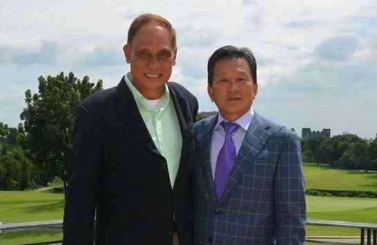 Tommy Manotoc smiling in a green shirt and black coat with a man