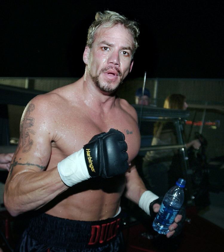 Tommy Morrison holding a water bottle and wearing black boxing gloves