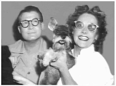 George Reeves smiling and wearing eyeglasses and Toni Mannix smiling while carrying their beloved dog, Sam