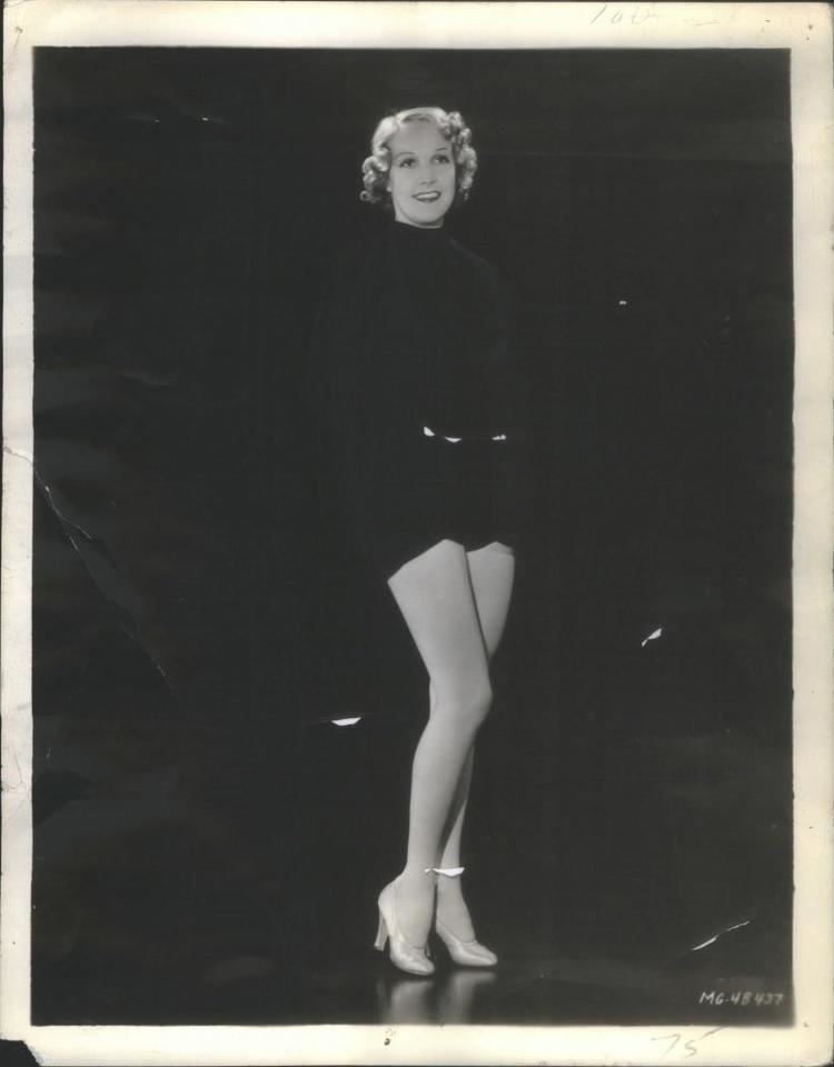 Toni Mannix smiling while wearing a black dress and heels