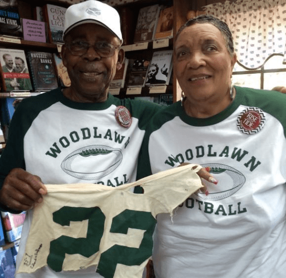 Tony Nathan with his wife smiling while holding a ripped part of his old jersey with the number 22