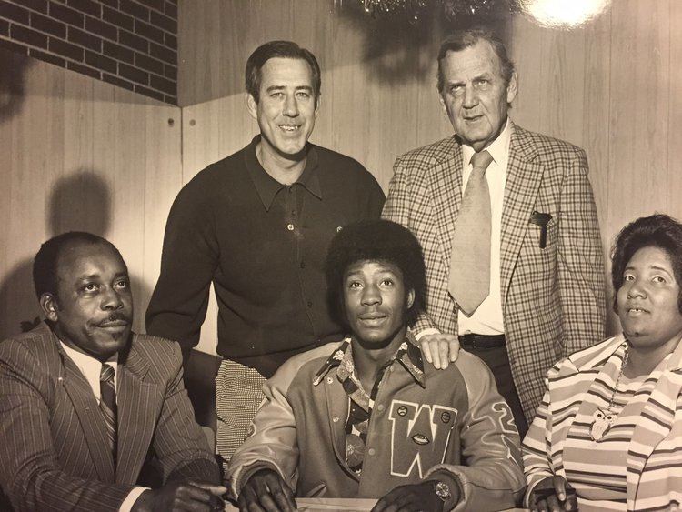 Tony Nathan sitting flanked by his parents. Standing behind are Alabama basketball coach C.M. Newton and football coach Paul Bryant