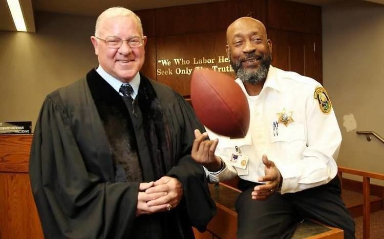 Ed Newman in his black court dress smiling together with Tony Nathan in his bailiff uniform inside the Miami-Dade courtroom